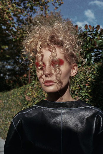 Girl with Curly Blonde Hair Red Eye Make Up and Leather Top